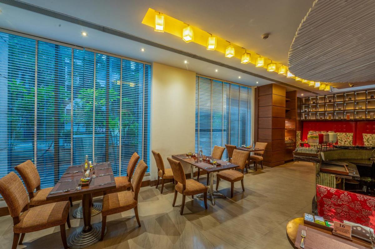 a restaurant with tables and chairs and large windows at O Hotel Pune in Pune