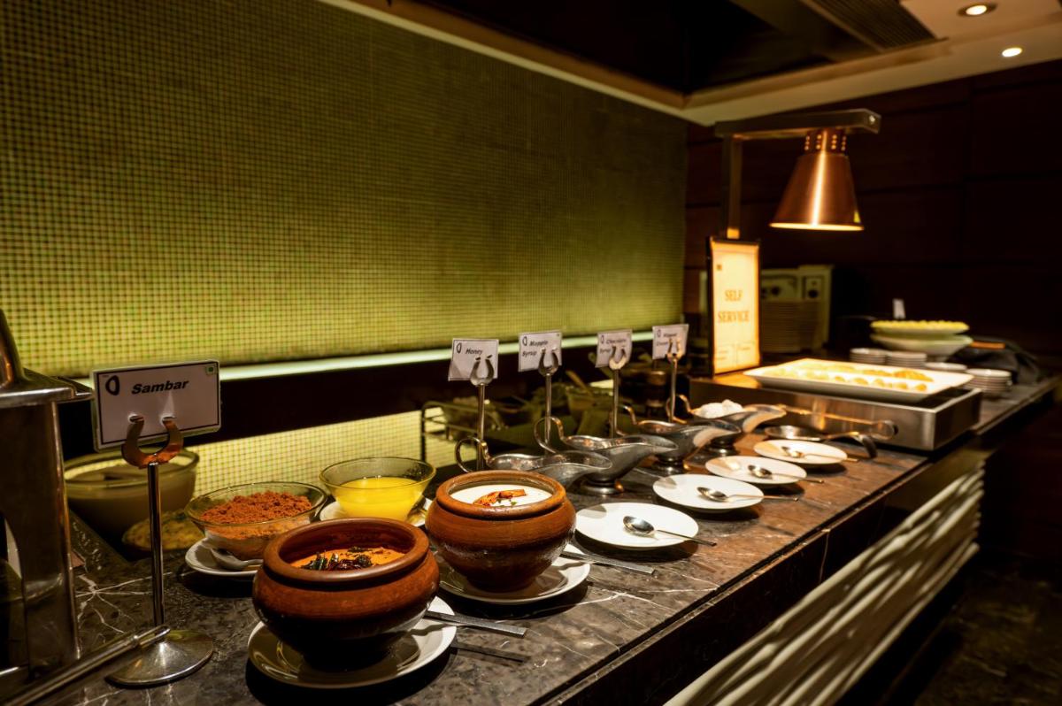 a kitchen with many plates of food on a counter at O Hotel Pune in Pune