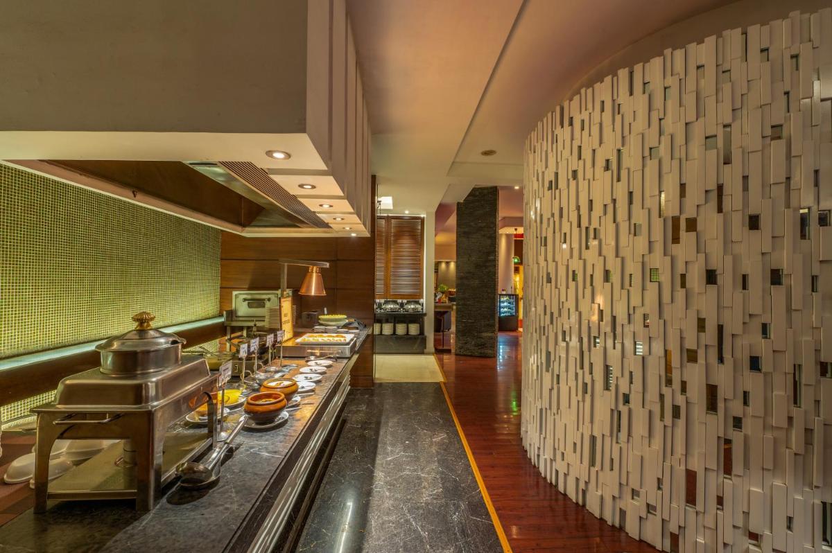 a kitchen with a buffet line in a restaurant at O Hotel Pune in Pune