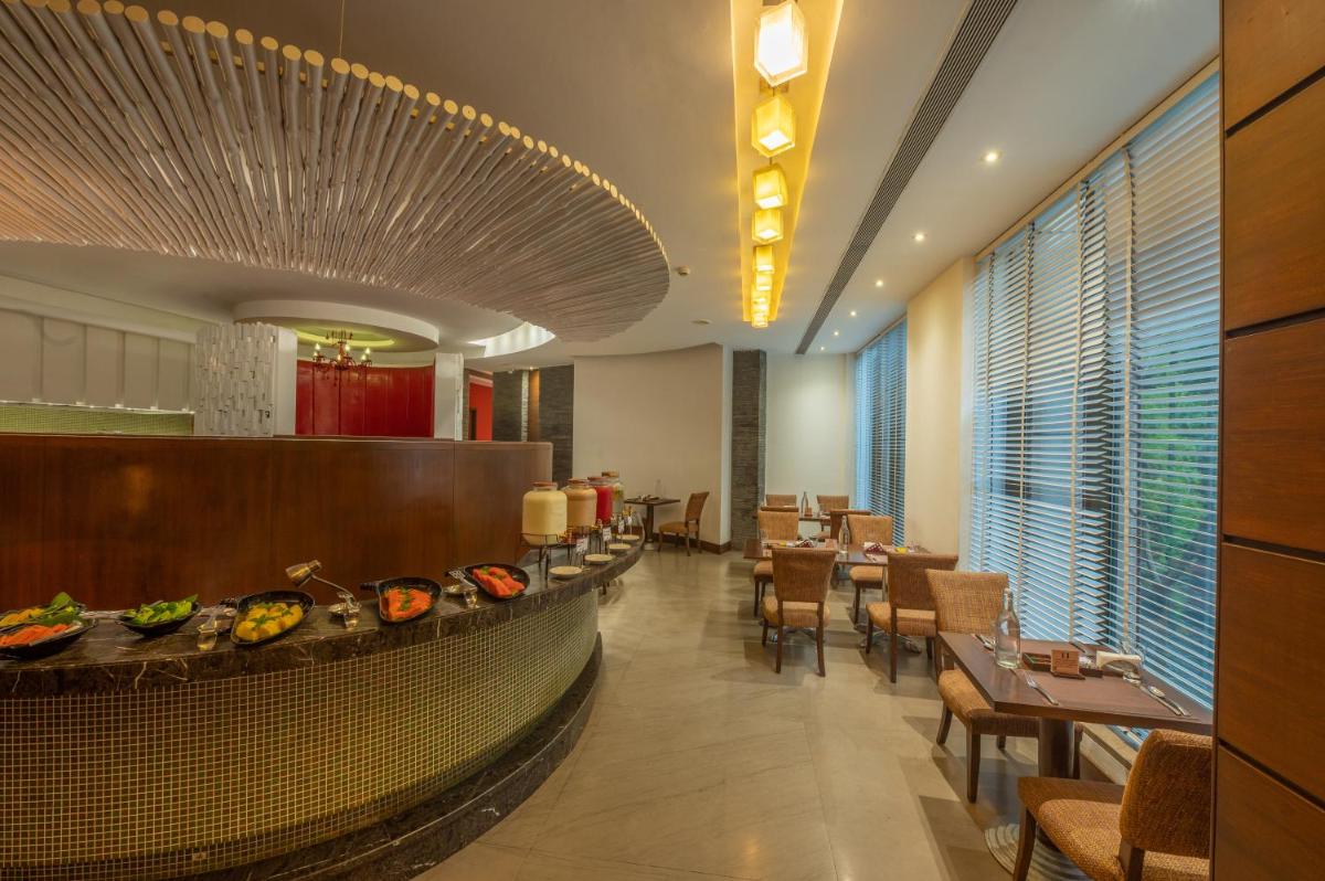 a restaurant with tables and chairs and a buffet at O Hotel Pune in Pune