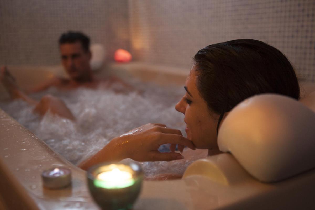 un hombre y una mujer en una bañera con una vela en Hotel Balneario de la Concepción, en Villatoya