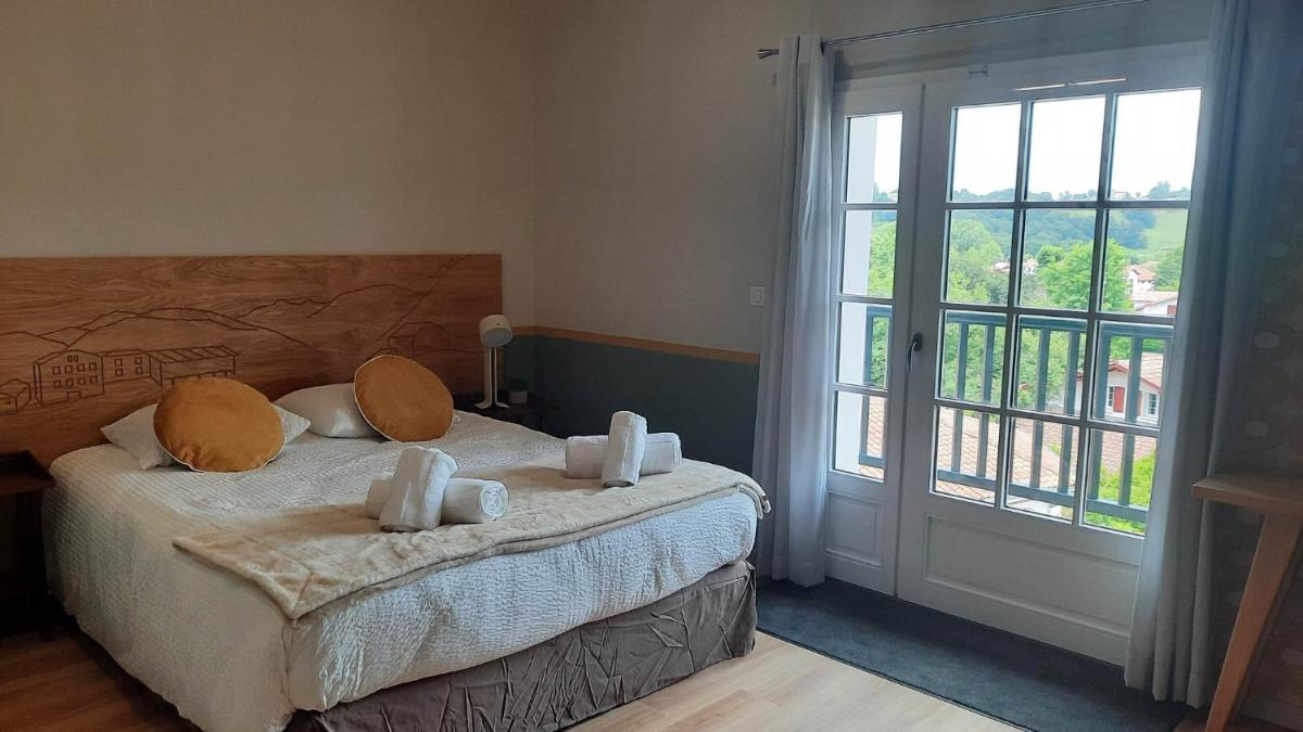 une chambre avec un lit et une grande fenêtre dans l'établissement Hotel Trinquet, à Saint-Pée-sur-Nivelle