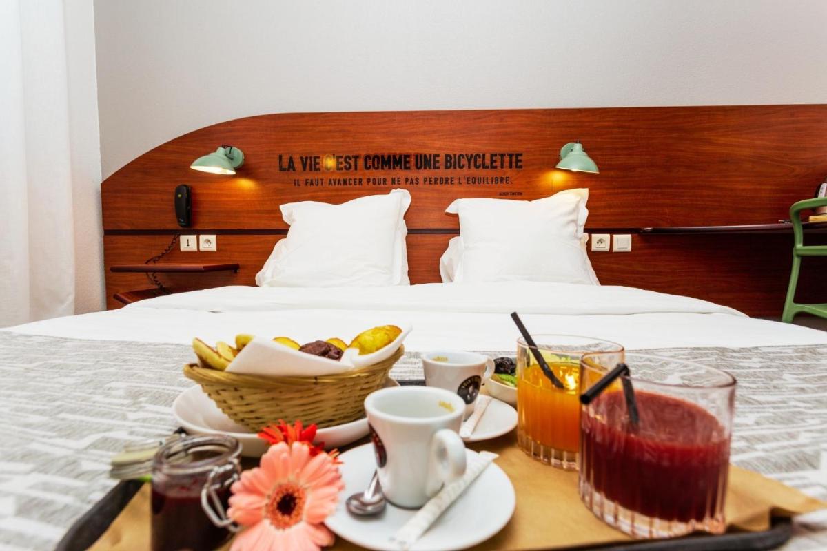 un plateau de nourriture et de boissons sur un lit dans l'établissement Sporting House Hôtel, à Toulouse