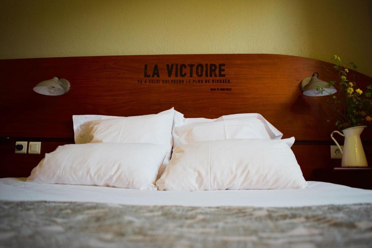 un lit avec des oreillers blancs et une tête de lit en bois dans l'établissement Sporting House Hôtel, à Toulouse