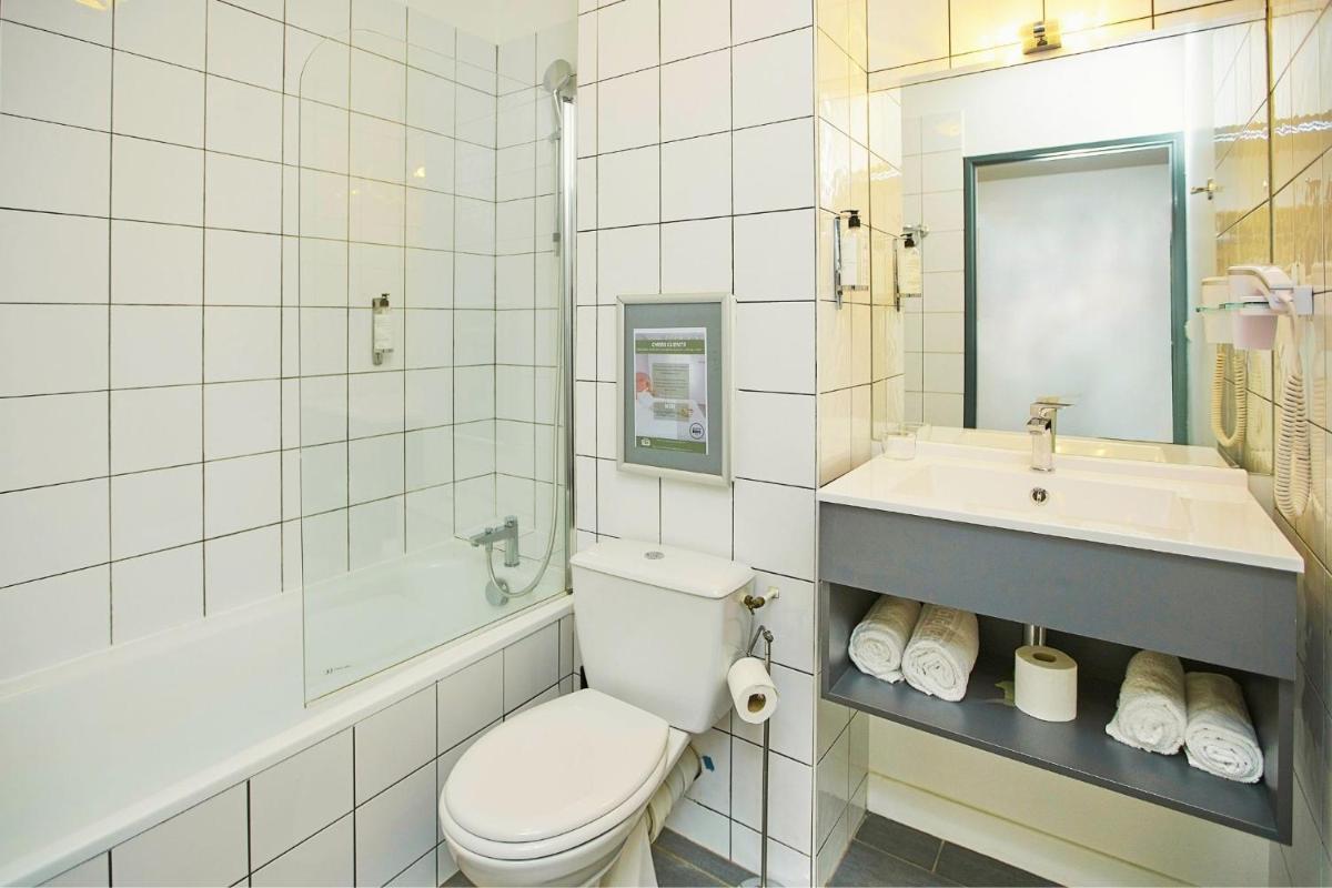 une salle de bains blanche avec toilettes et lavabo dans l'établissement Sporting House Hôtel, à Toulouse