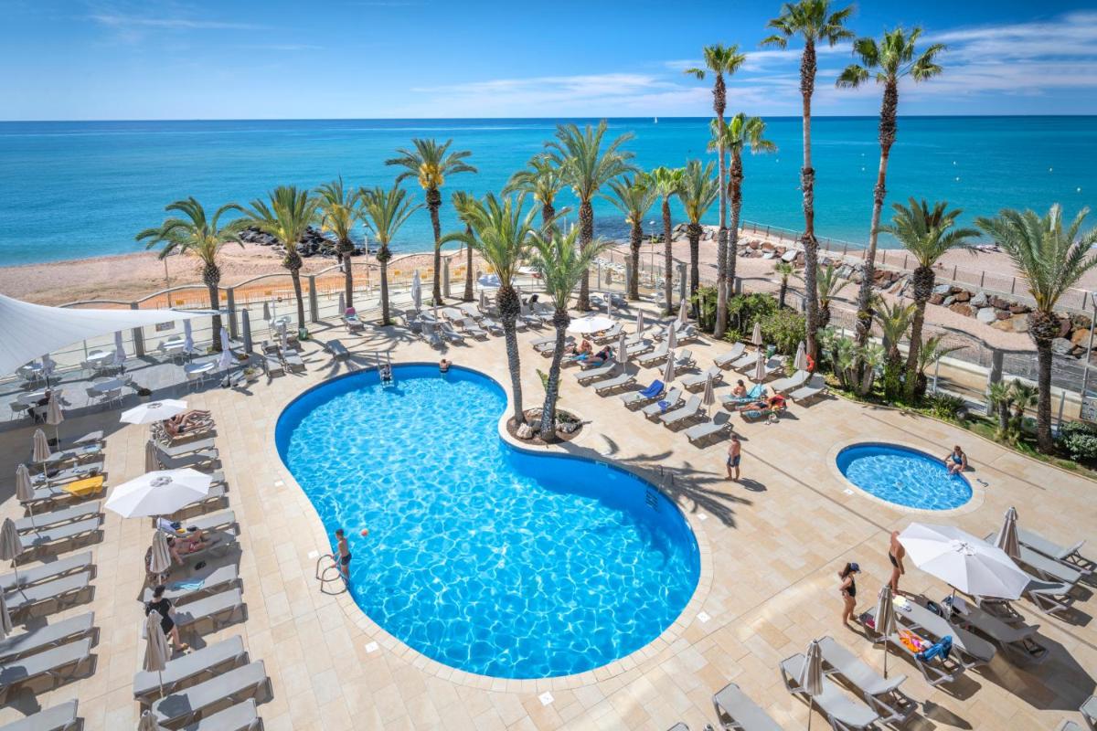 Una vista aérea de una piscina y la playa. en Caprici Beach Hotel & Spa, en Santa Susanna