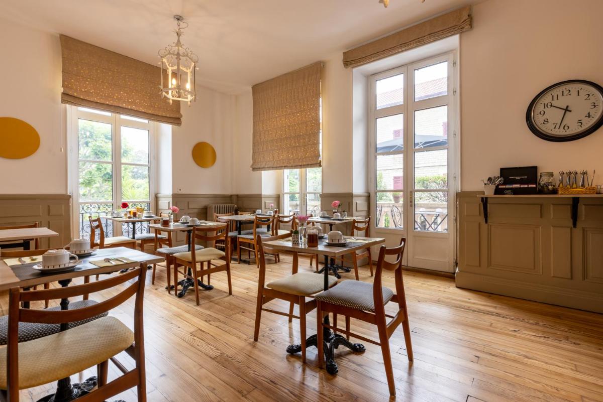 un restaurant avec des tables et des chaises et une horloge au mur dans l'établissement Hôtel & Espace Bien-être La Maison du Lierre, à Biarritz