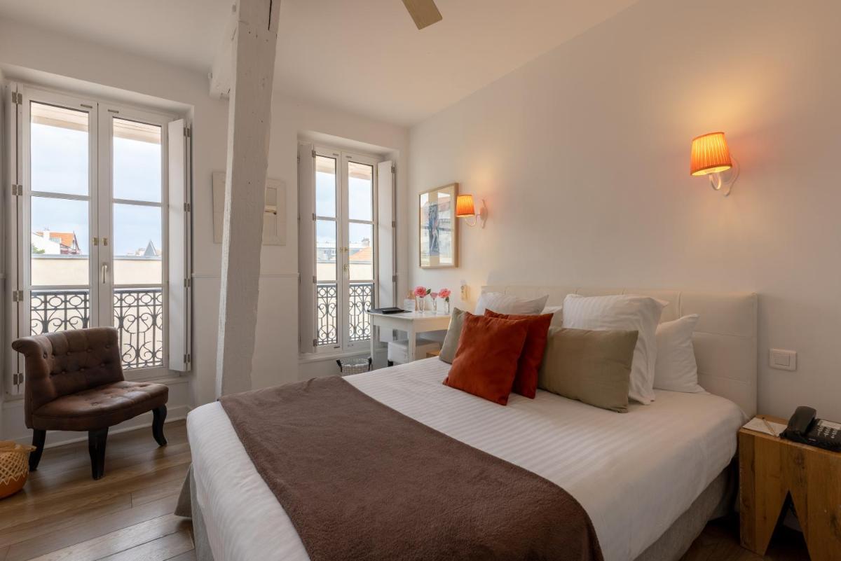 une chambre avec un grand lit et une chaise dans l'établissement Hôtel & Espace Bien-être La Maison du Lierre, à Biarritz