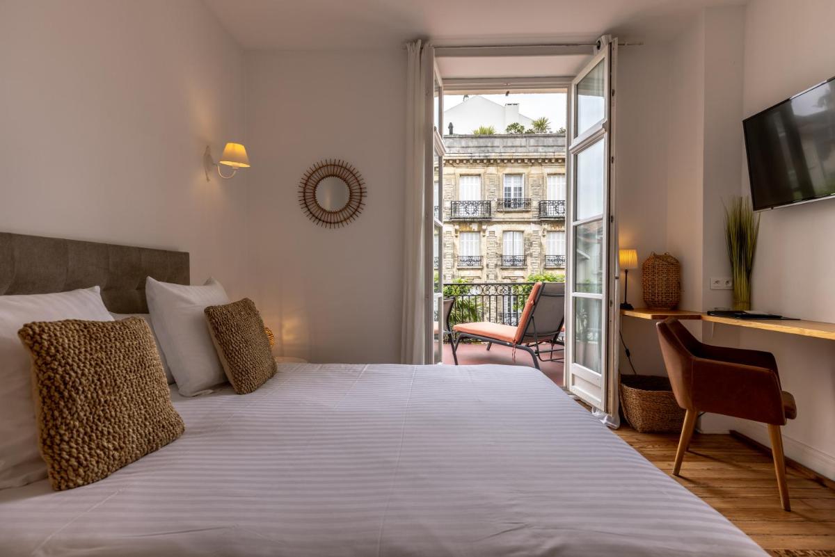 une chambre avec un grand lit et un balcon dans l'établissement Hôtel & Espace Bien-être La Maison du Lierre, à Biarritz