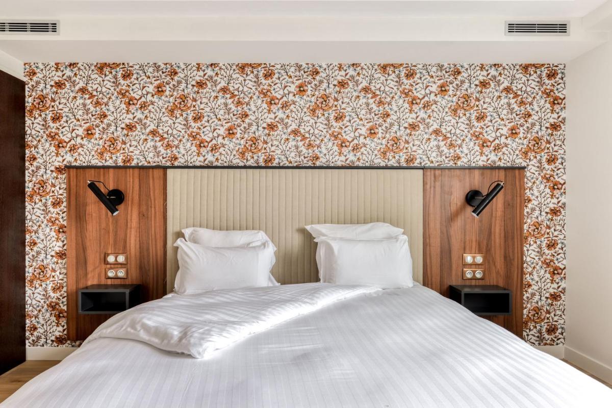 une chambre avec un grand lit blanc à tête de lit en bois dans l'établissement Zenitude Hotel La Valadière, Ascend Hotel Collection, à Montpellier
