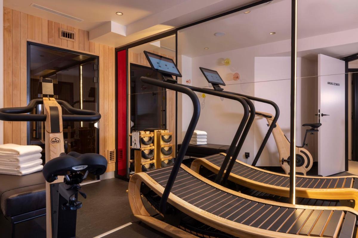 une salle de sport avec deux tapis de course et un tapis roulant dans l'établissement Le 12 Hôtel, à Paris