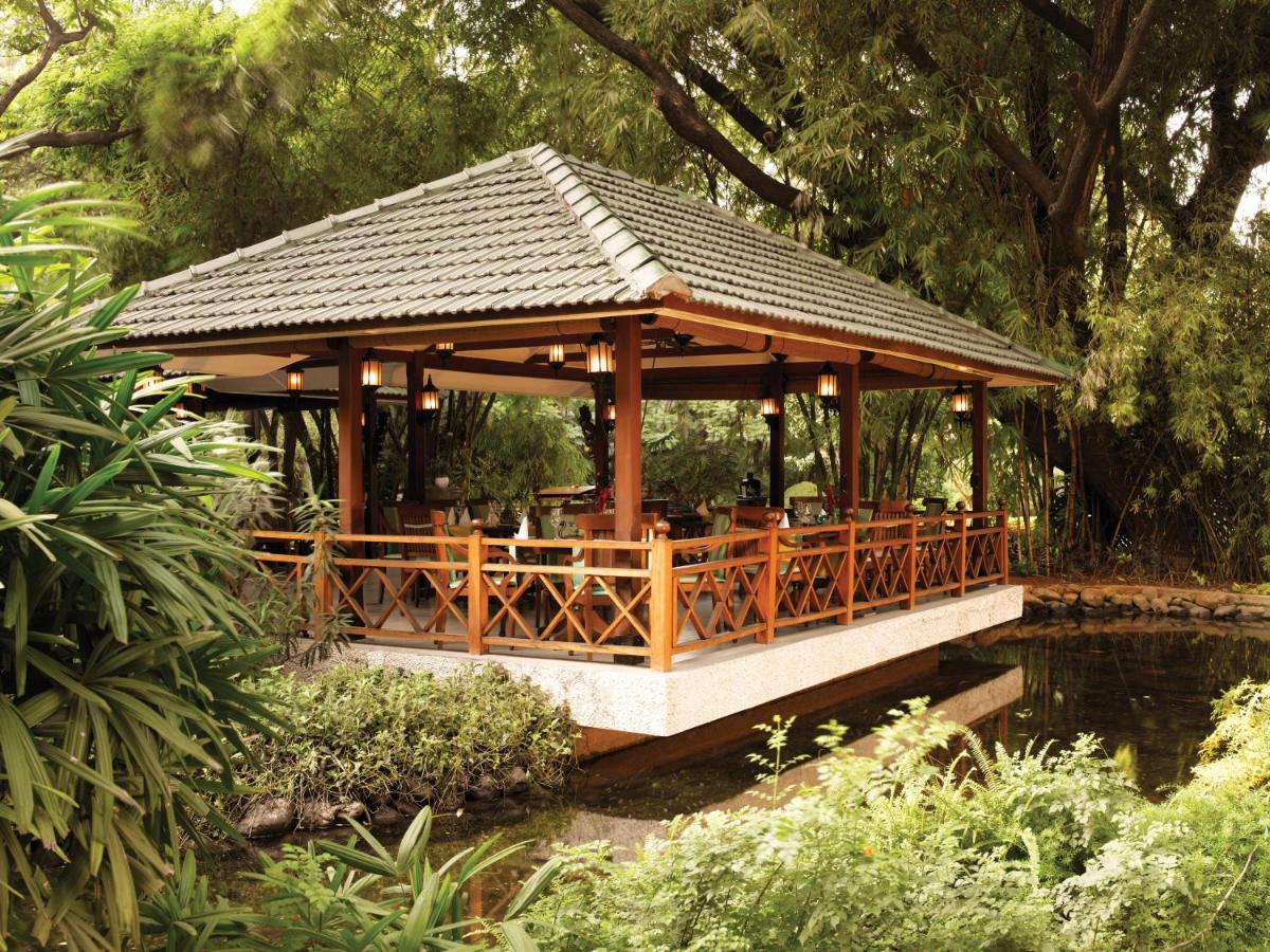 a gazebo in a garden next to a pond at The Oberoi Bengaluru in Bengaluru a gazebo in a garden next to a pond at The Oberoi Bengaluru in Bengaluru