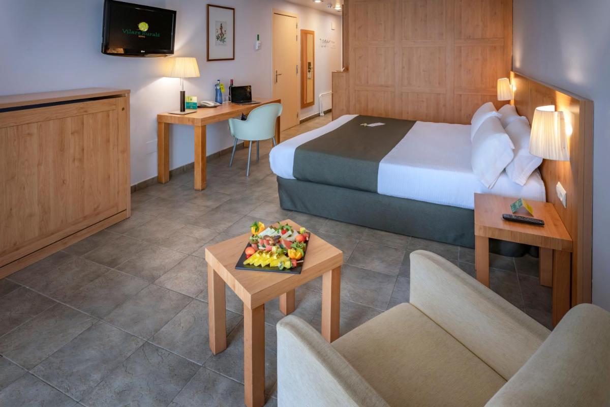 una habitación de hotel con una cama y una mesa con un pastel en Vilar Rural De Sant Hilari Sacalm by Serhs Hotels, en Sant Hilari Sacalm