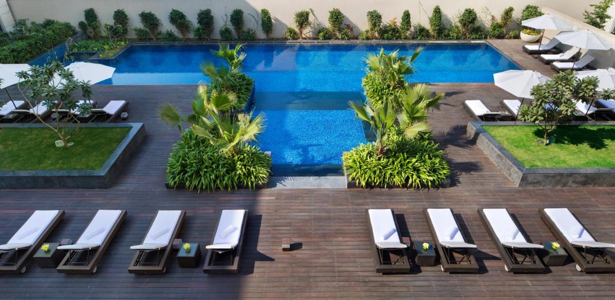 an overhead view of a swimming pool with white lounge chairs at JW Marriott Hotel New Delhi Aerocity in New Delhi an overhead view of a swimming pool with white lounge chairs at JW Marriott Hotel New Delhi Aerocity in New Delhi