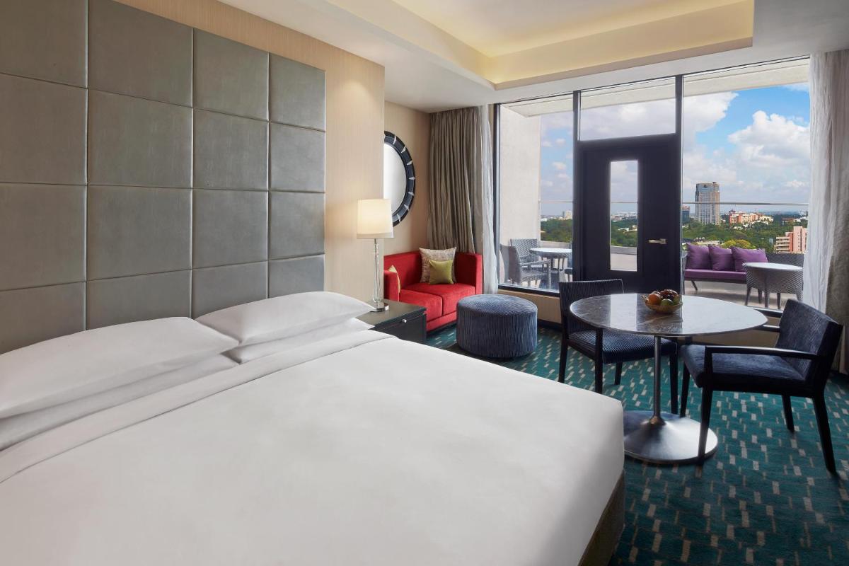 a bedroom with a bed and a room with a view at Renaissance Bengaluru Race Course Hotel in Bengaluru