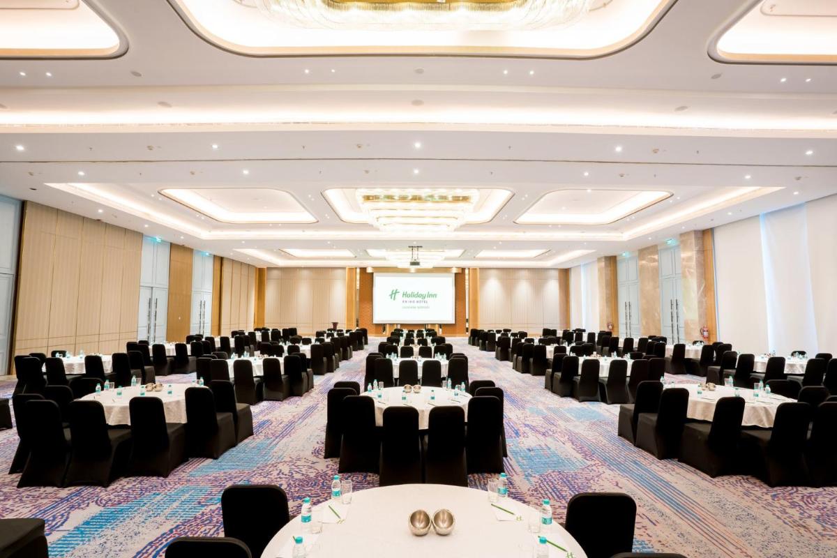 a large room with tables and chairs and a projection screen at Holiday Inn Lucknow Airport by IHG in Lucknow