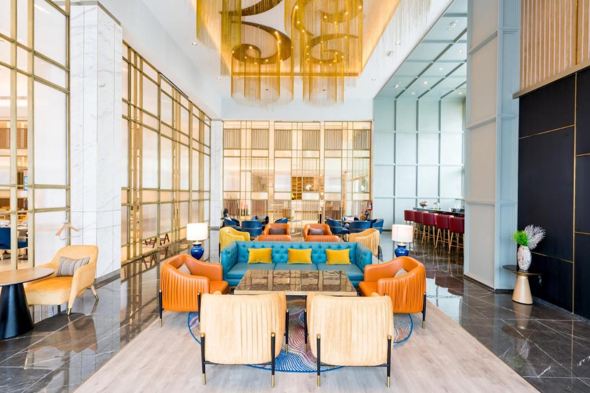 a lobby with orange chairs and a blue couch at Holiday Inn Lucknow Airport by IHG in Lucknow