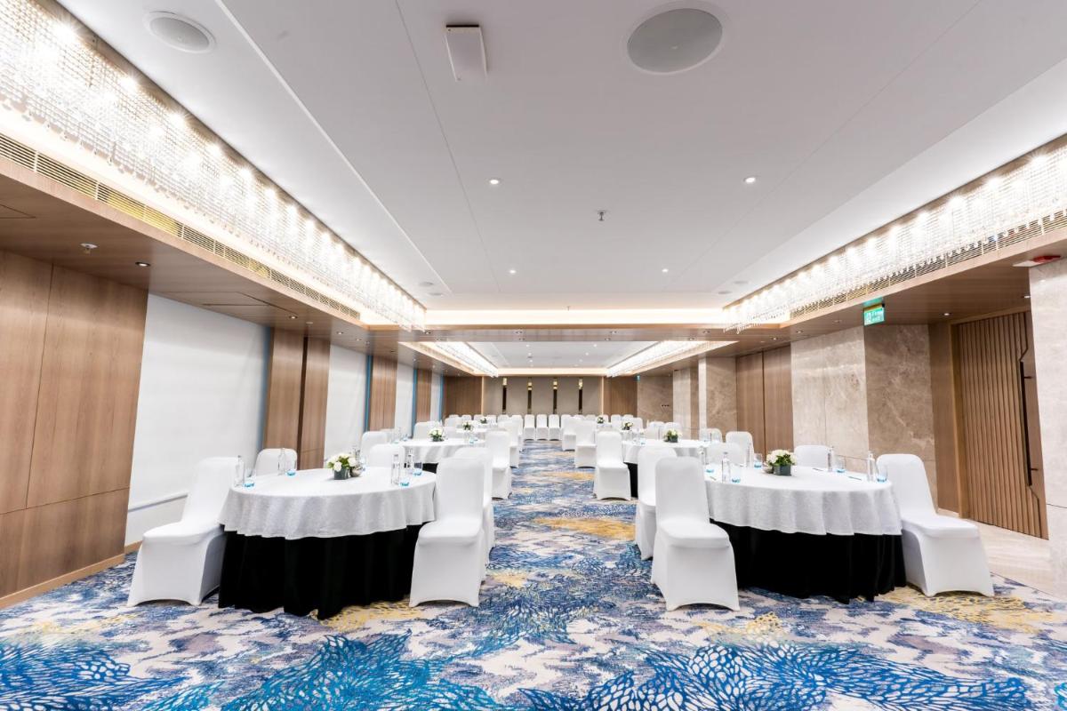 a banquet hall with white tables and white chairs at Holiday Inn Lucknow Airport by IHG in Lucknow