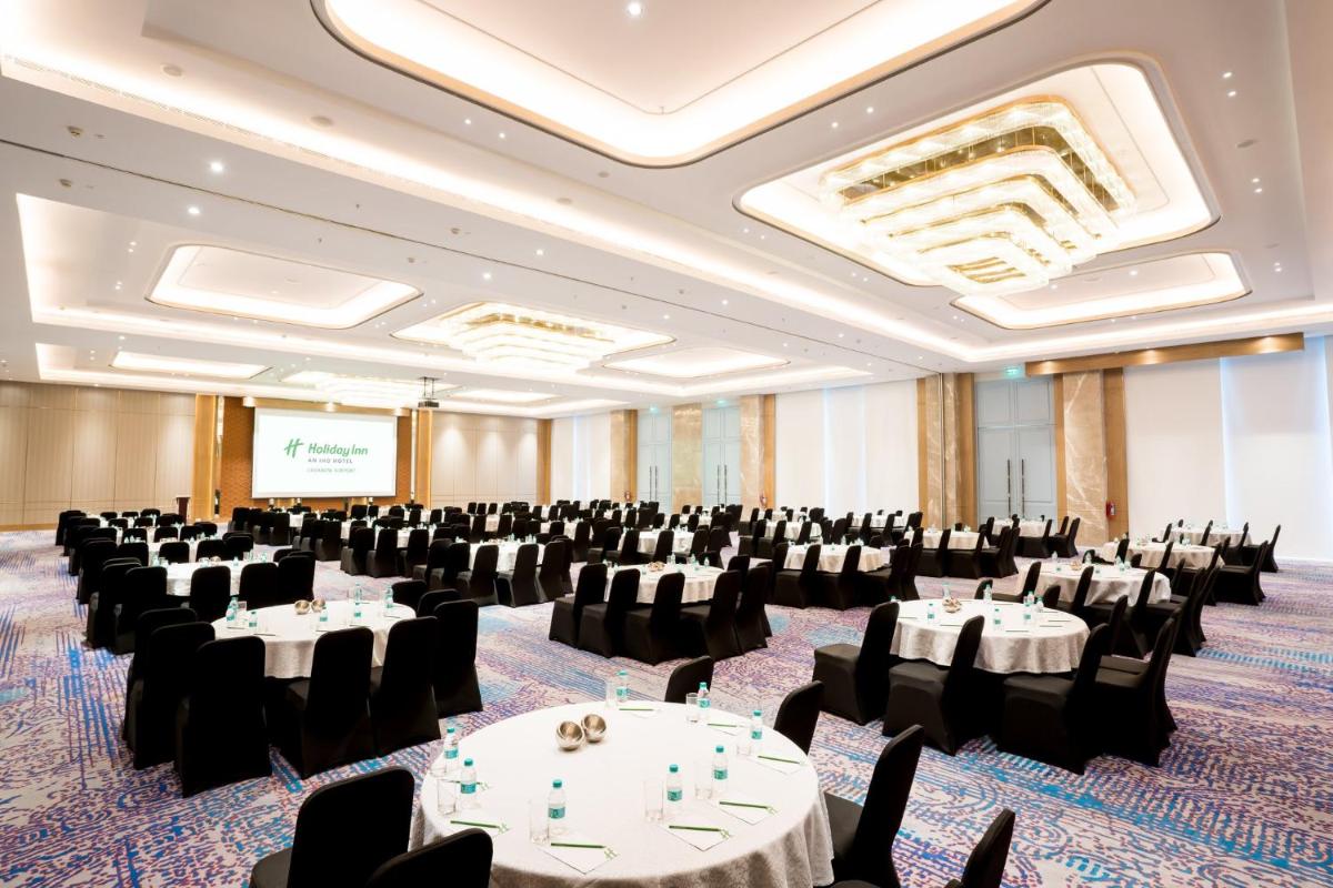 a conference room with tables and chairs and a screen at Holiday Inn Lucknow Airport by IHG in Lucknow