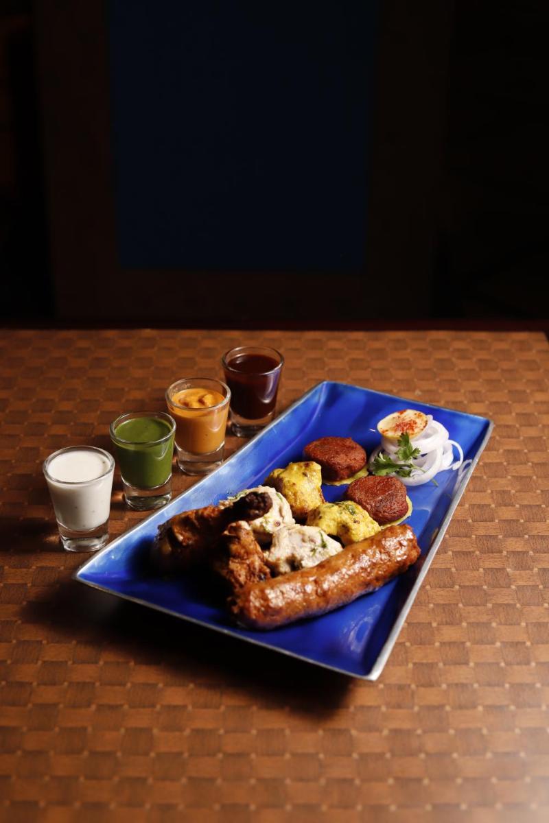 a blue plate with sausage and other foods on a table at Radisson Jaipur City Center in Jaipur