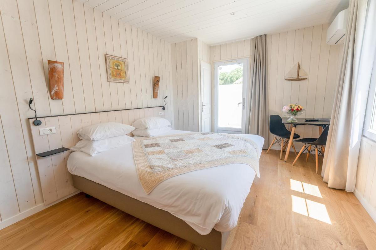 une chambre avec un grand lit et un bureau dans l'établissement Hôtel Restaurant & Spa Plaisir, au Bois-Plage-en-Ré