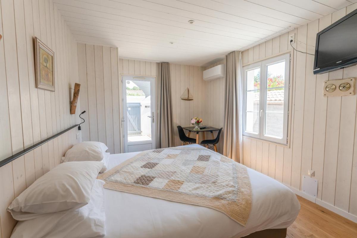 - une chambre avec un lit et une télévision murale dans l'établissement Hôtel Restaurant & Spa Plaisir, au Bois-Plage-en-Ré 97 autres photos