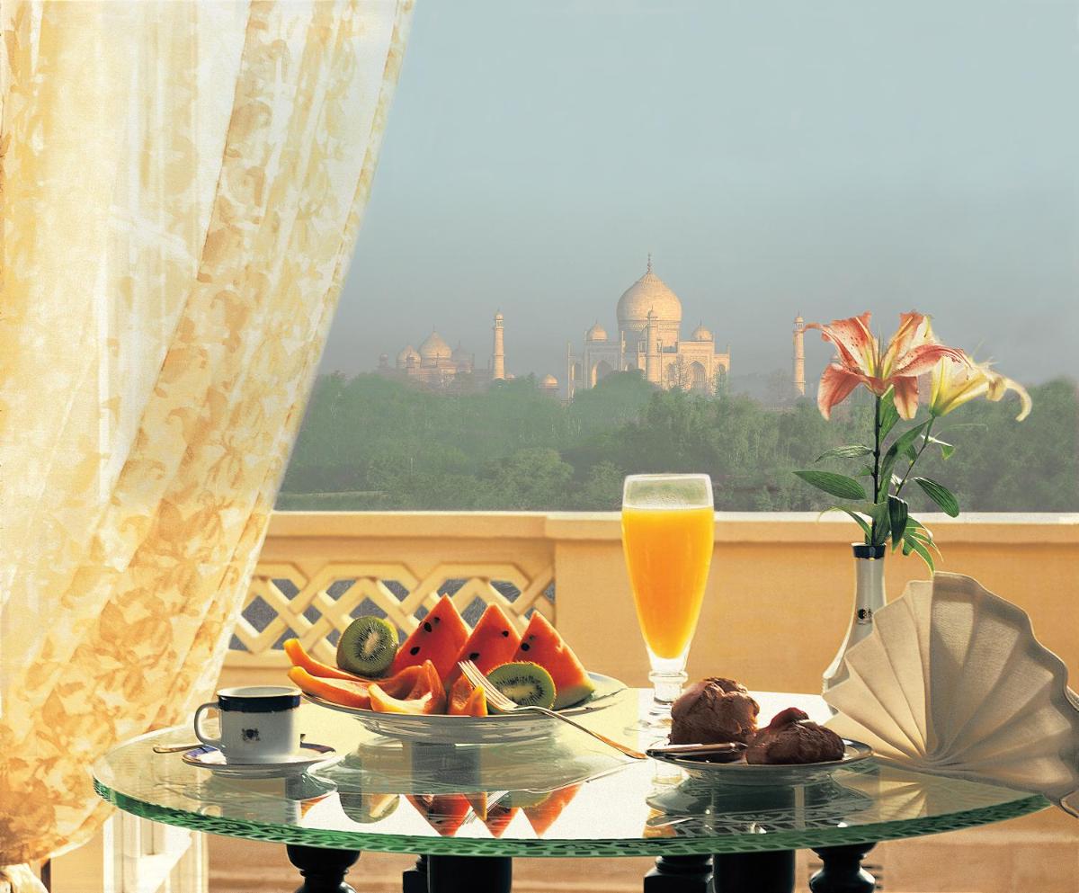 a glass table with a plate of fruit and orange juice at The Oberoi Amarvilas Agra in Agra
