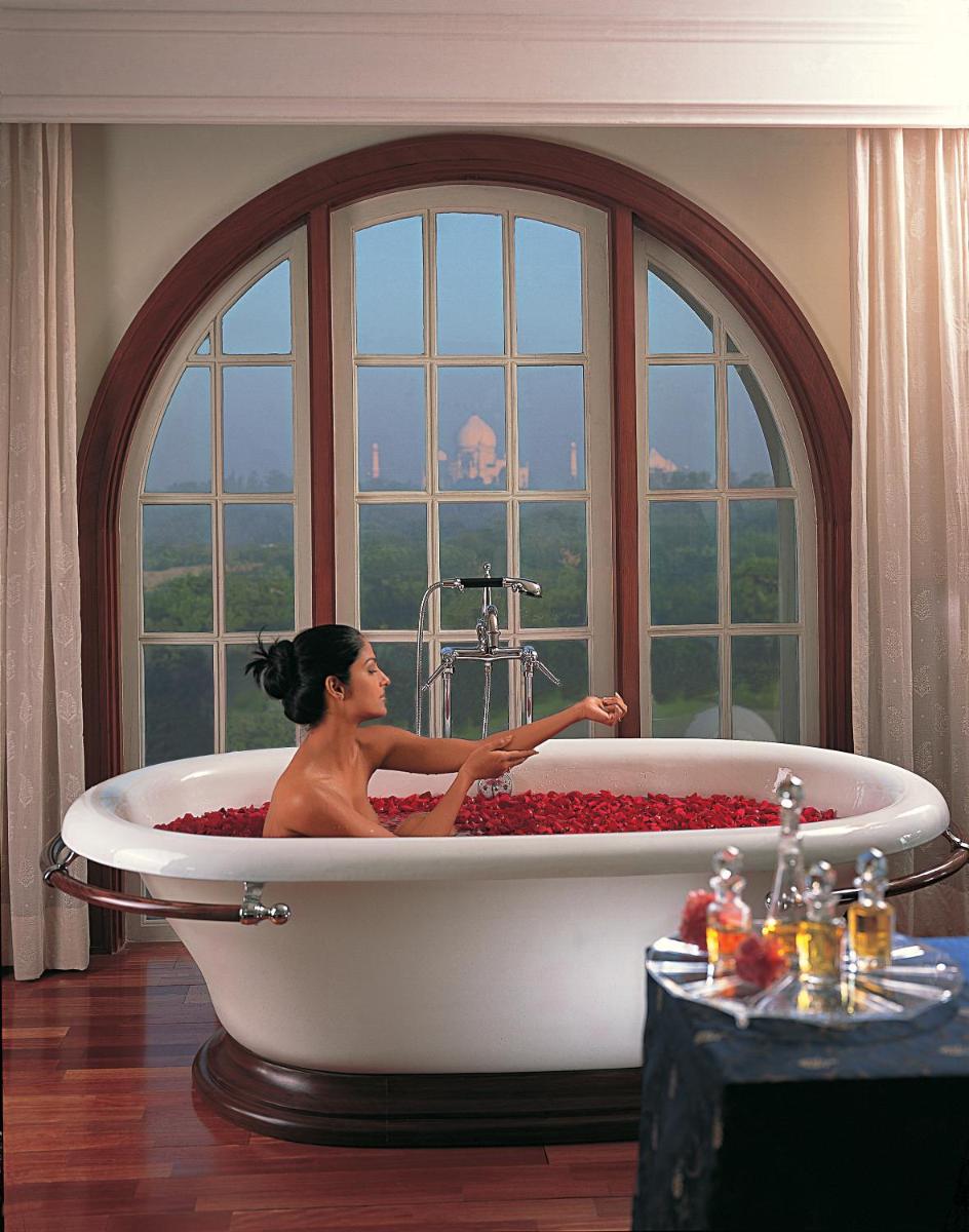 a woman sitting in a bath tub in front of a window at The Oberoi Amarvilas Agra in Agra