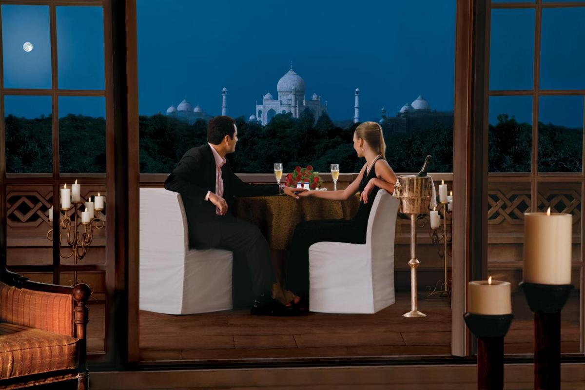 a man and woman sitting at a table in a restaurant at The Oberoi Amarvilas Agra in Agra