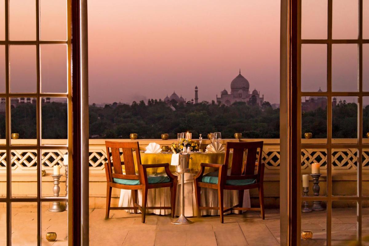 a table with chairs and a view of the taj mahal at The Oberoi Amarvilas Agra in Agra