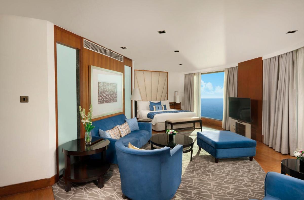 a living room with a blue couch and a bed at InterContinental Marine Drive Mumbai by IHG in Mumbai