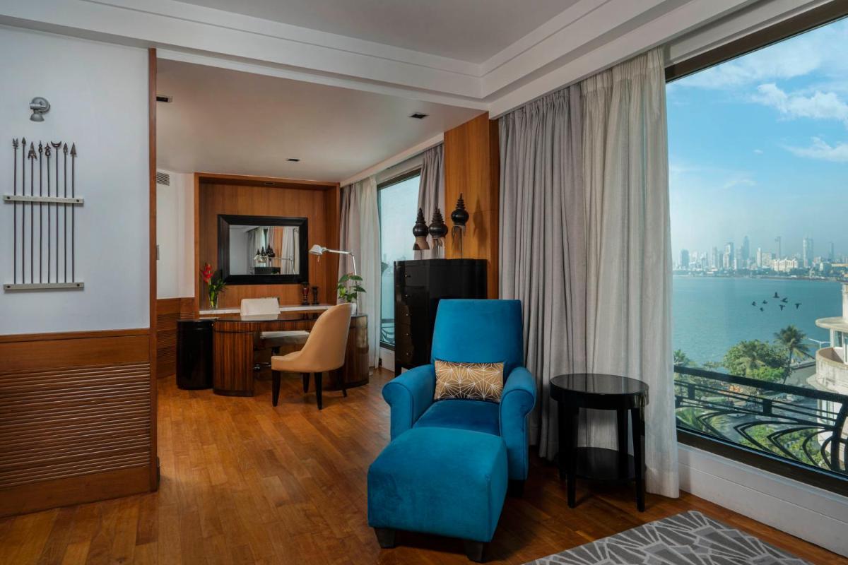 a living room with a blue chair and a room with a view at InterContinental Marine Drive Mumbai by IHG in Mumbai