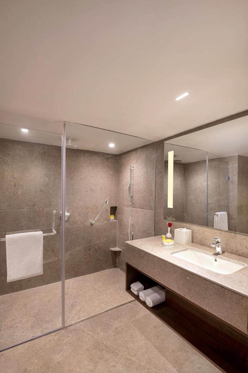 a bathroom with a sink and a shower and a mirror at Hyatt Centric Rajpur Road Dehradun in Dehradun