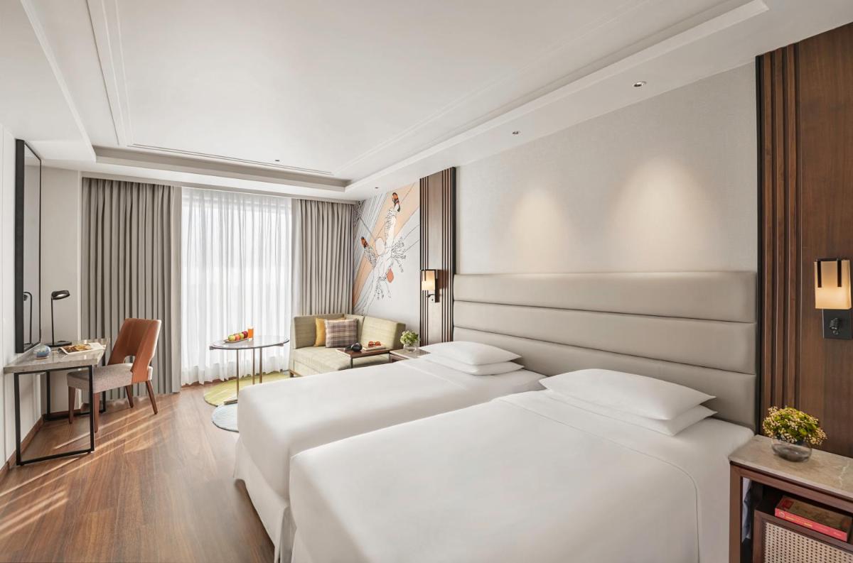 a hotel room with two beds and a living room at Hyatt Centric Rajpur Road Dehradun in Dehradun
