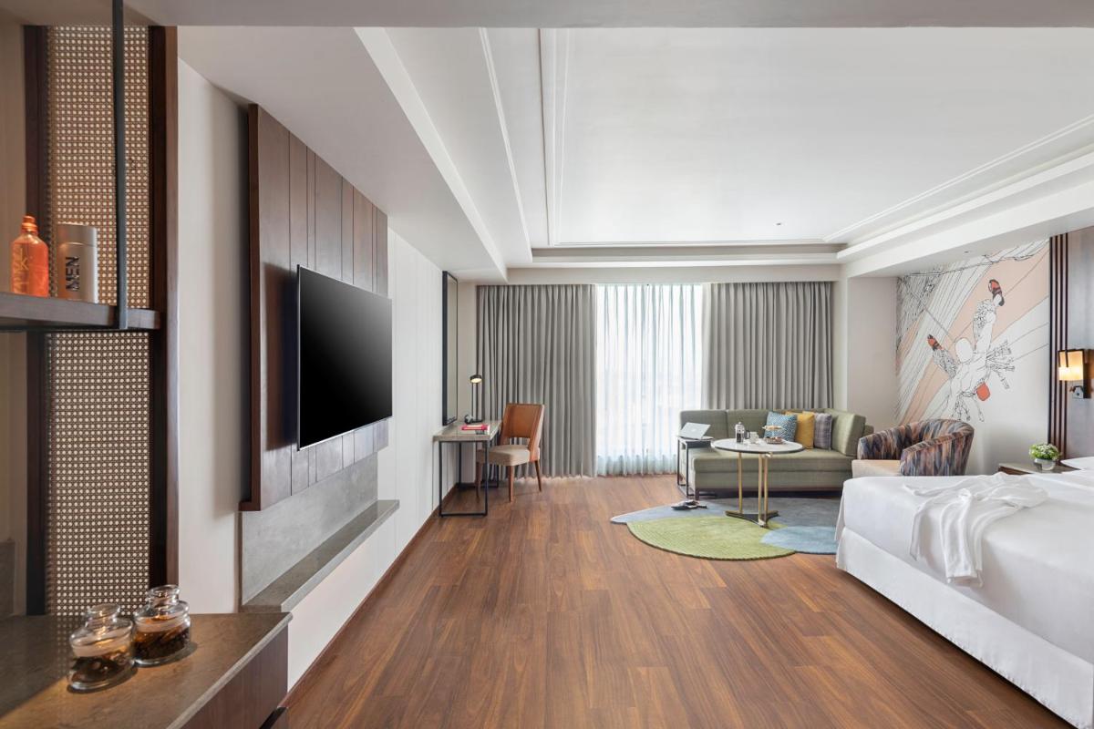 a bedroom with a bed and a living room at Hyatt Centric Rajpur Road Dehradun in Dehradun