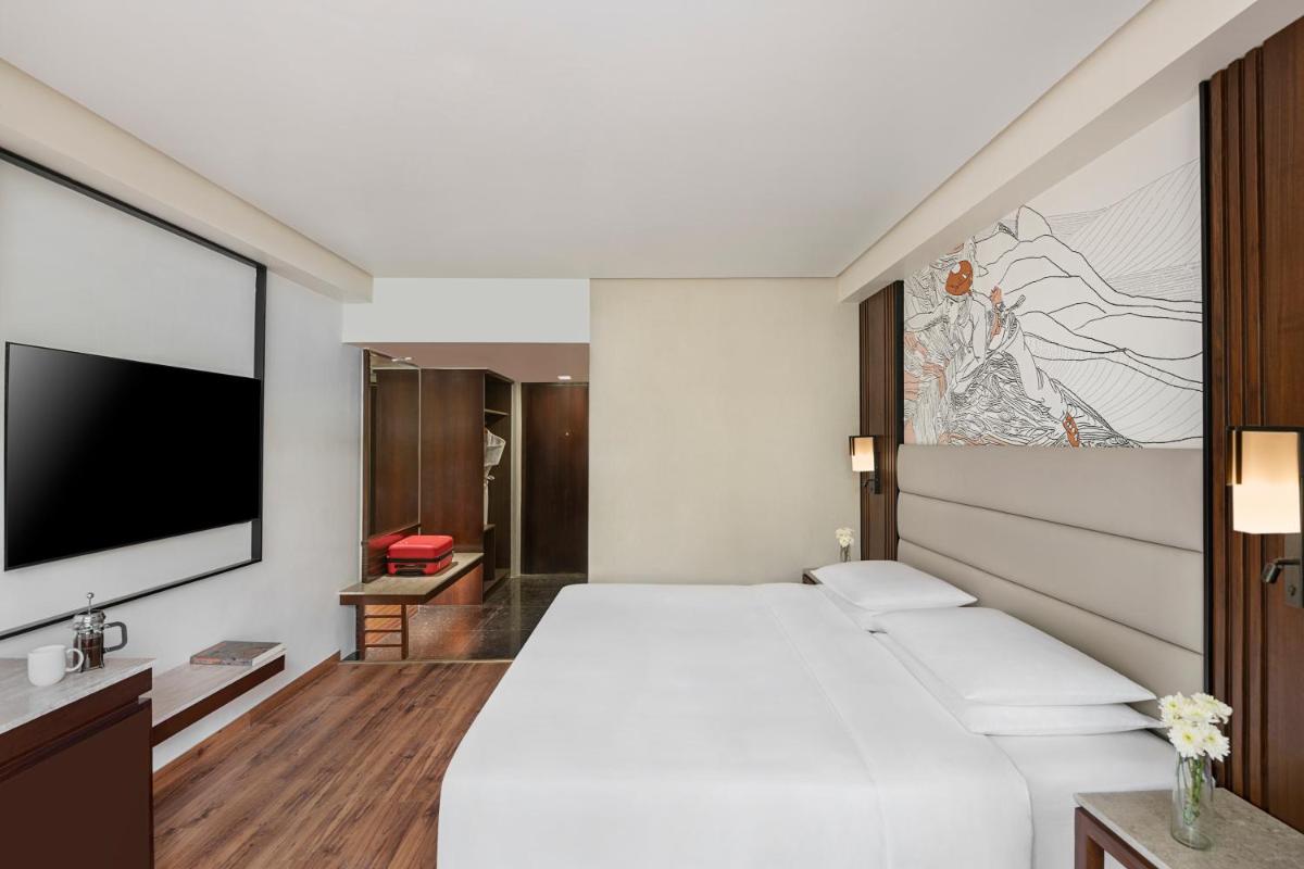 a bedroom with a large bed and a flat screen tv at Hyatt Centric Rajpur Road Dehradun in Dehradun