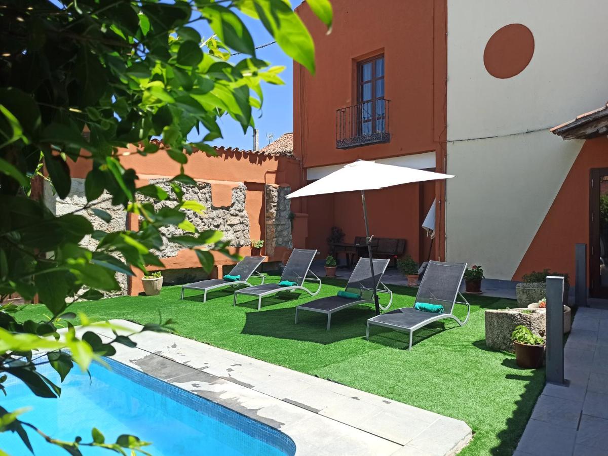 un patio con sillas, una sombrilla y una piscina en Hotel Casa del Abad, en Ampudia