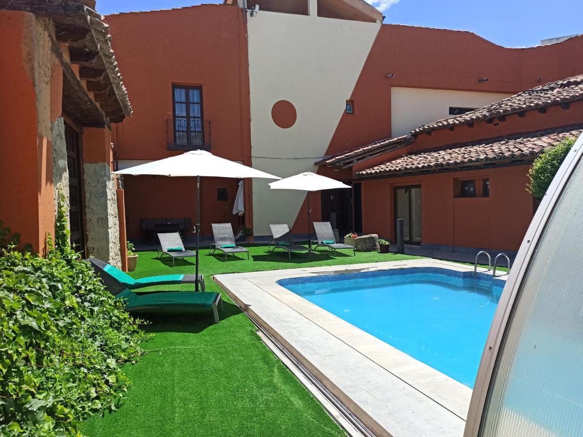 Una piscina en un patio con sillas y sombrillas. en Hotel Casa del Abad, en Ampudia