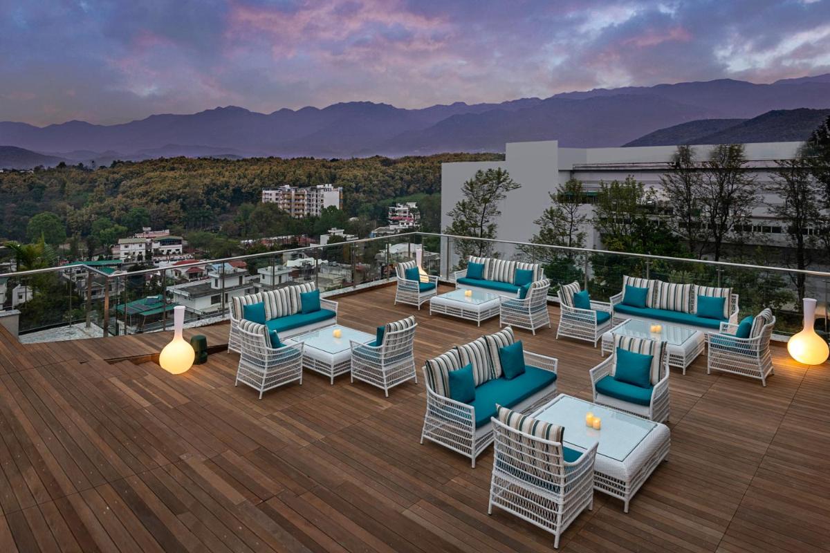 a deck with chairs and tables on top of a building at Hyatt Centric Rajpur Road Dehradun in Dehradun