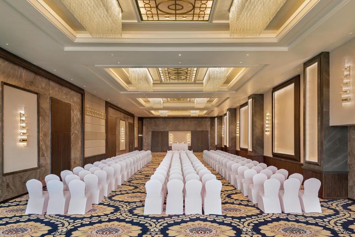 a row of white chairs in a room with a row of tables at Hyatt Centric Rajpur Road Dehradun in Dehradun