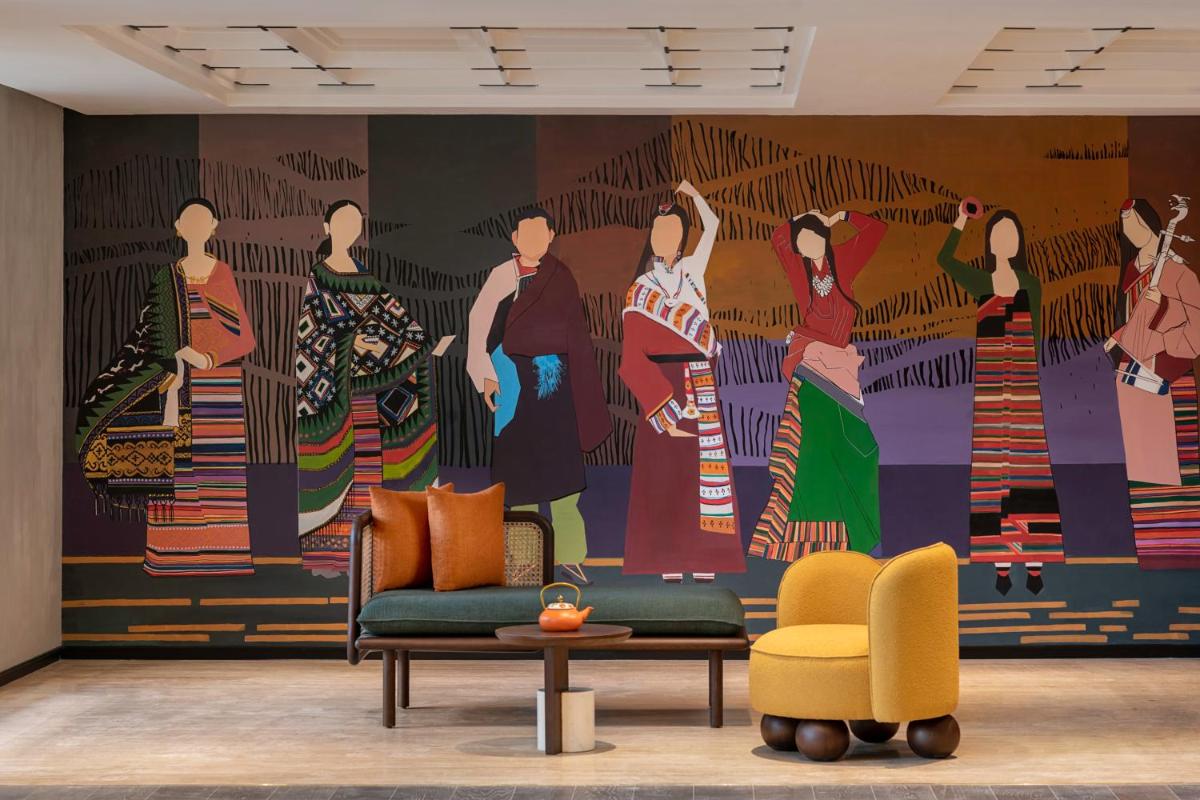 a living room with a mural of women on the wall at Hyatt Centric Rajpur Road Dehradun in Dehradun