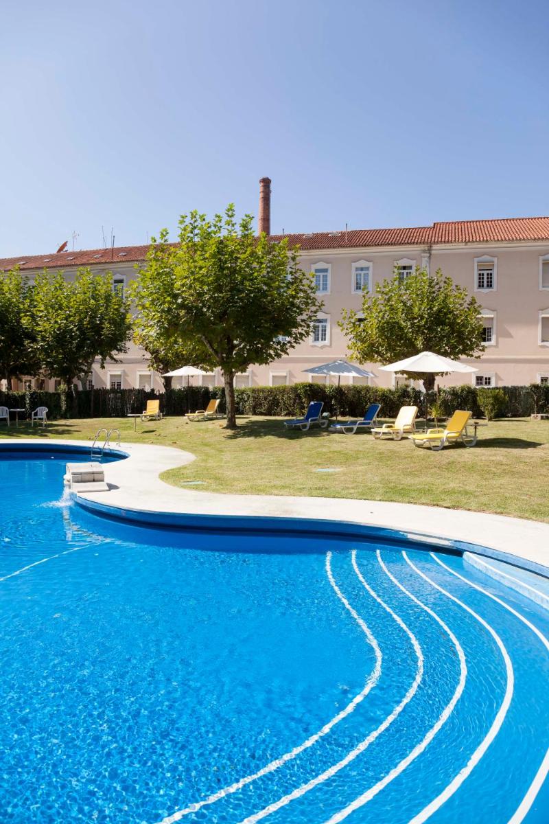 uma grande piscina com água azul em frente a um edifício em Hotel Termas da Curia em Curia