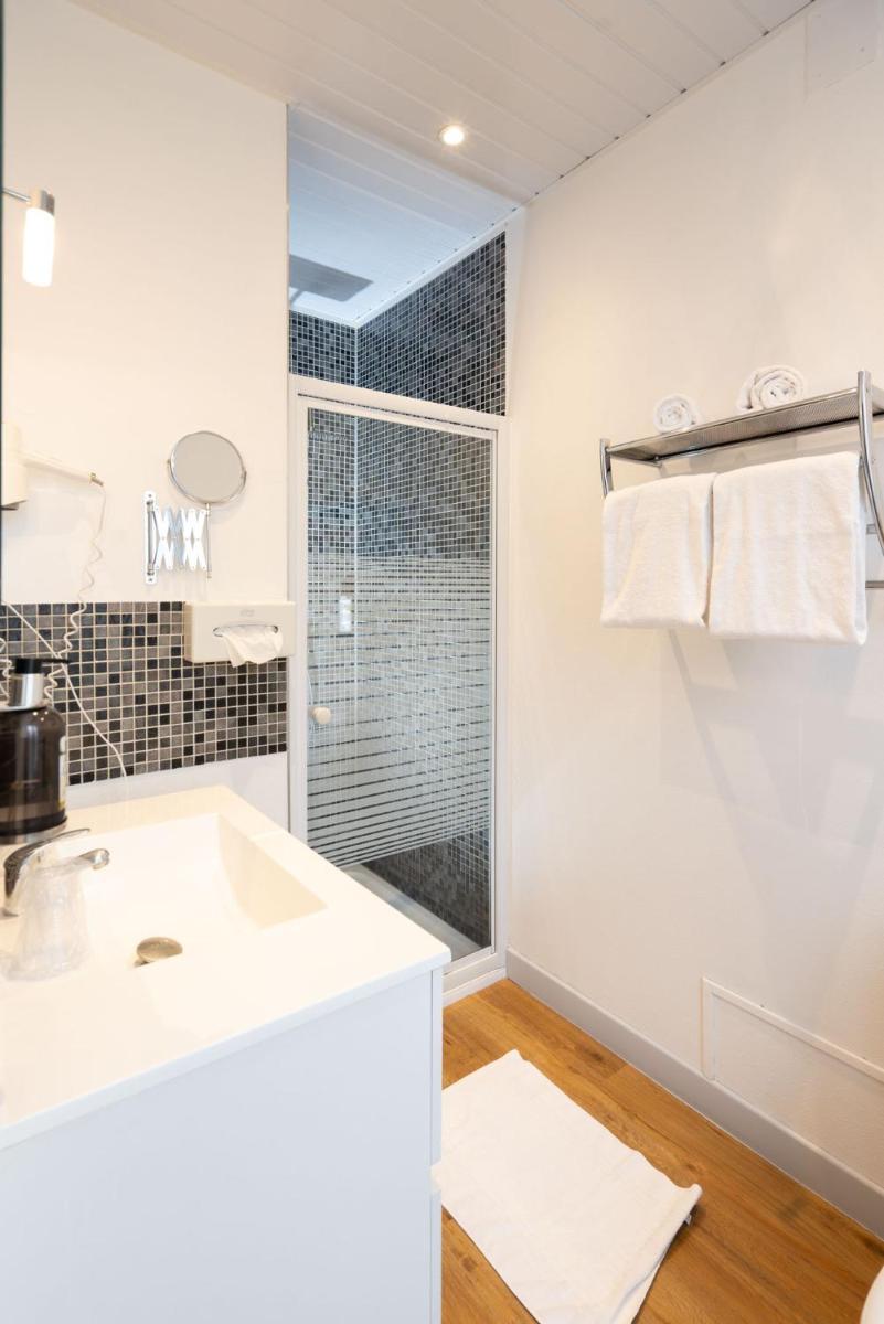 une salle de bain blanche avec un lavabo et une douche dans l'établissement Logis Central Hôtel - Restaurant & Spa, à Bort-les-Orgues 74 autres photos