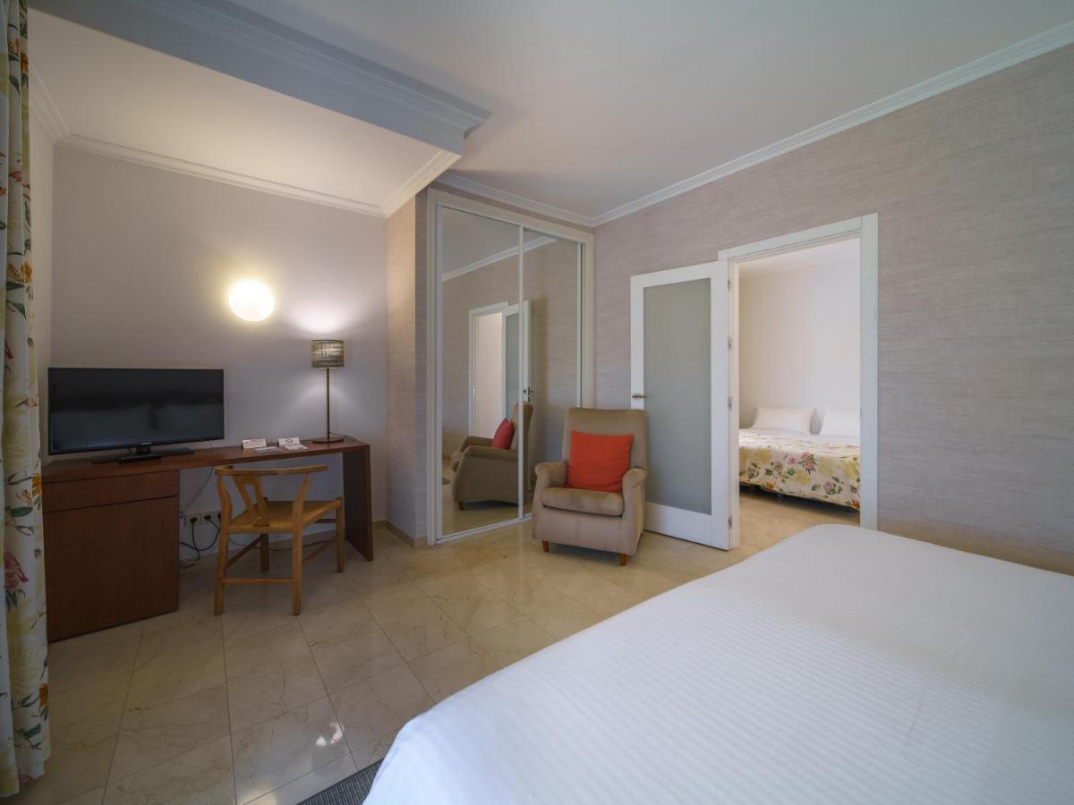Un dormitorio con una cama, un escritorio y un televisor. en Hotel Spa Atlántico San Vicente do Mar, en San Vicente do Mar