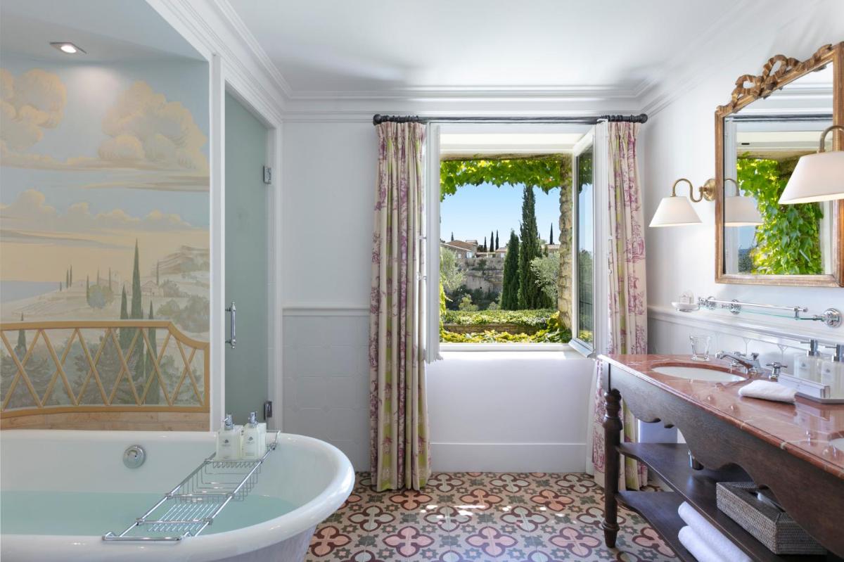 une salle de bain avec baignoire et une grande fenêtre dans l'établissement Airelles Gordes, La Bastide, à Gordes