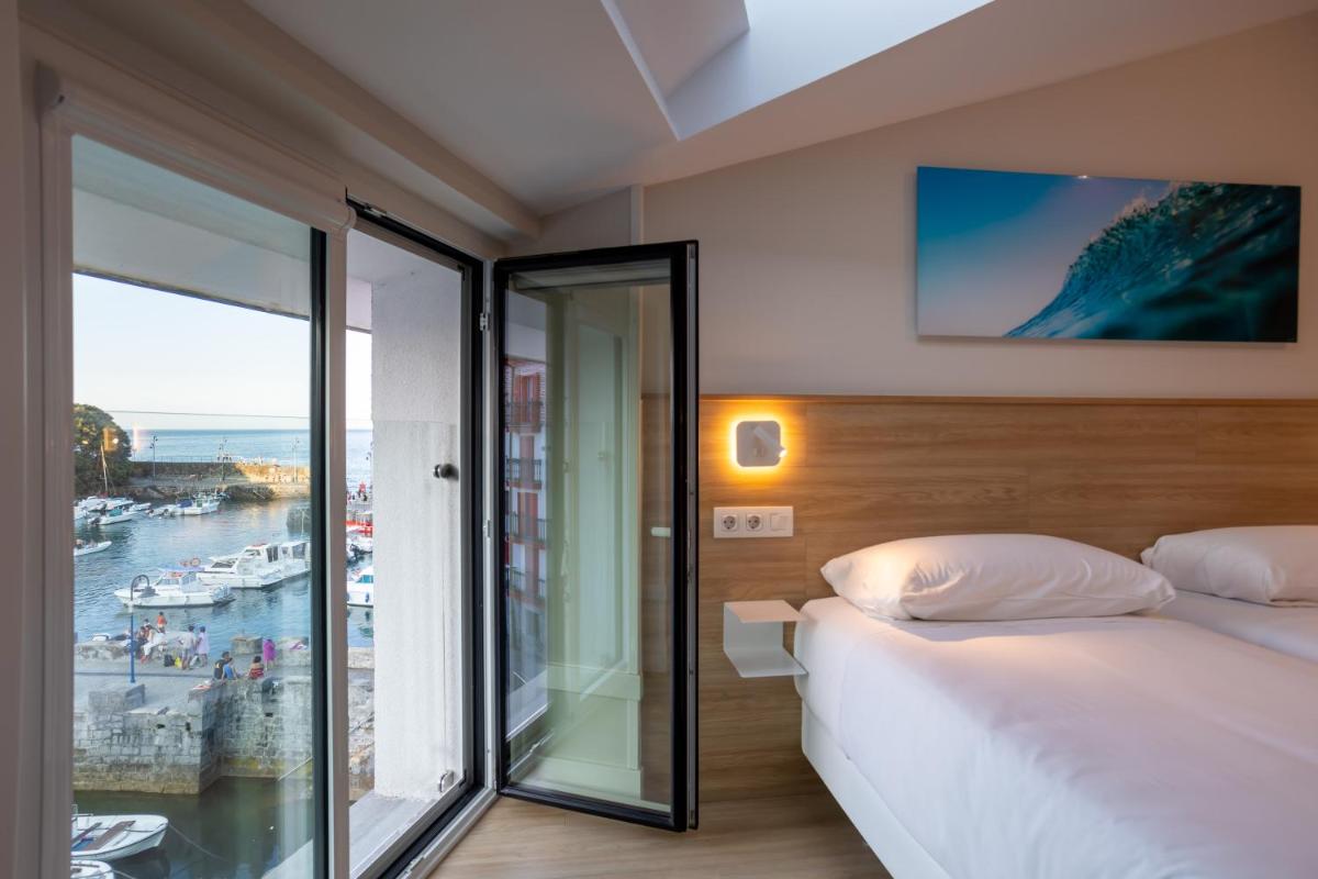 Un dormitorio con una cama y vista al mar. en Apartamentos&Spa Mundakaport, en Mundaka 52 fotos más