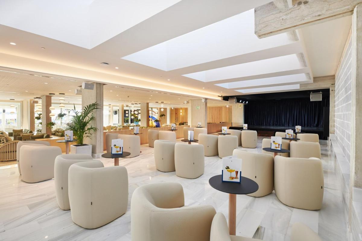 un vestíbulo con sillas y mesas blancas en una habitación en Hipotels Mediterraneo Hotel - Adults Only, en Sa Coma