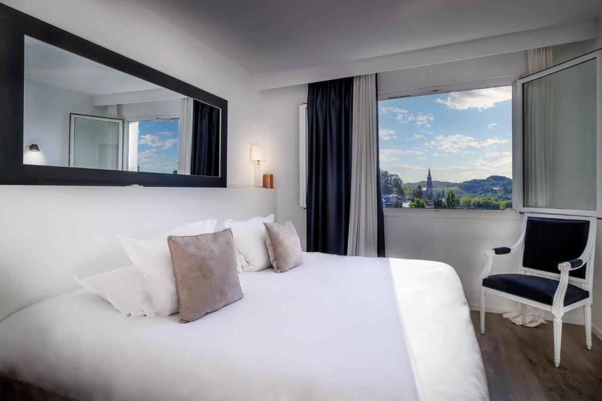 une chambre avec un lit blanc et une grande fenêtre dans l'établissement Belfry & Spa by Ligne St Barth, à Lourdes
