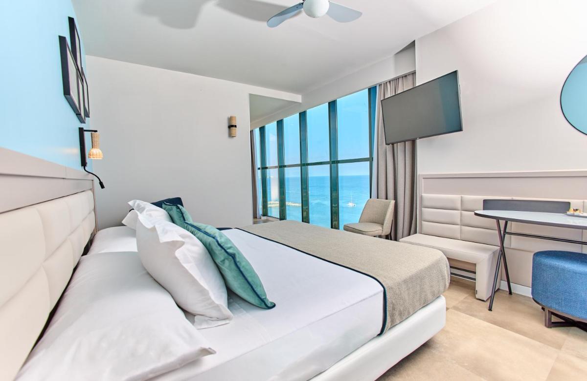 Un dormitorio con una cama, un escritorio y un televisor. en Leonardo Hotel Fuengirola Costa del Sol, en Fuengirola