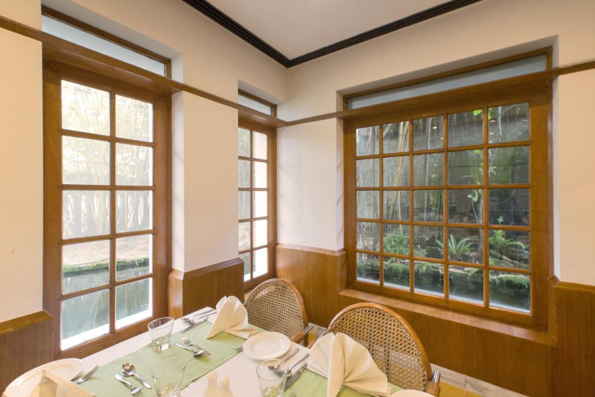 a dining room with tables and chairs and windows at Casino Hotel - CGH Earth, Cochin in Cochin